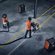 Ouvrier de la construction aux commandes d’une surfaceuse intérieure dotée d’aspirateurs industriels connectés.