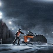 Bouwvakker die 's nachts een krachtknipper gebruikt op een natte bouwplaats.