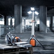 コンクリートの床にパワーカッター、作業灯、掃除機がある建設現場。