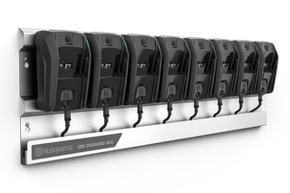 Un rail de charge Husqvarna sur lequel sont montés huit chargeurs de batterie.